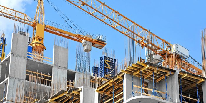 Crane and building construction site against blue sky